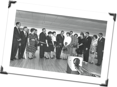 black and white photo of men and women standing on a bowling lane